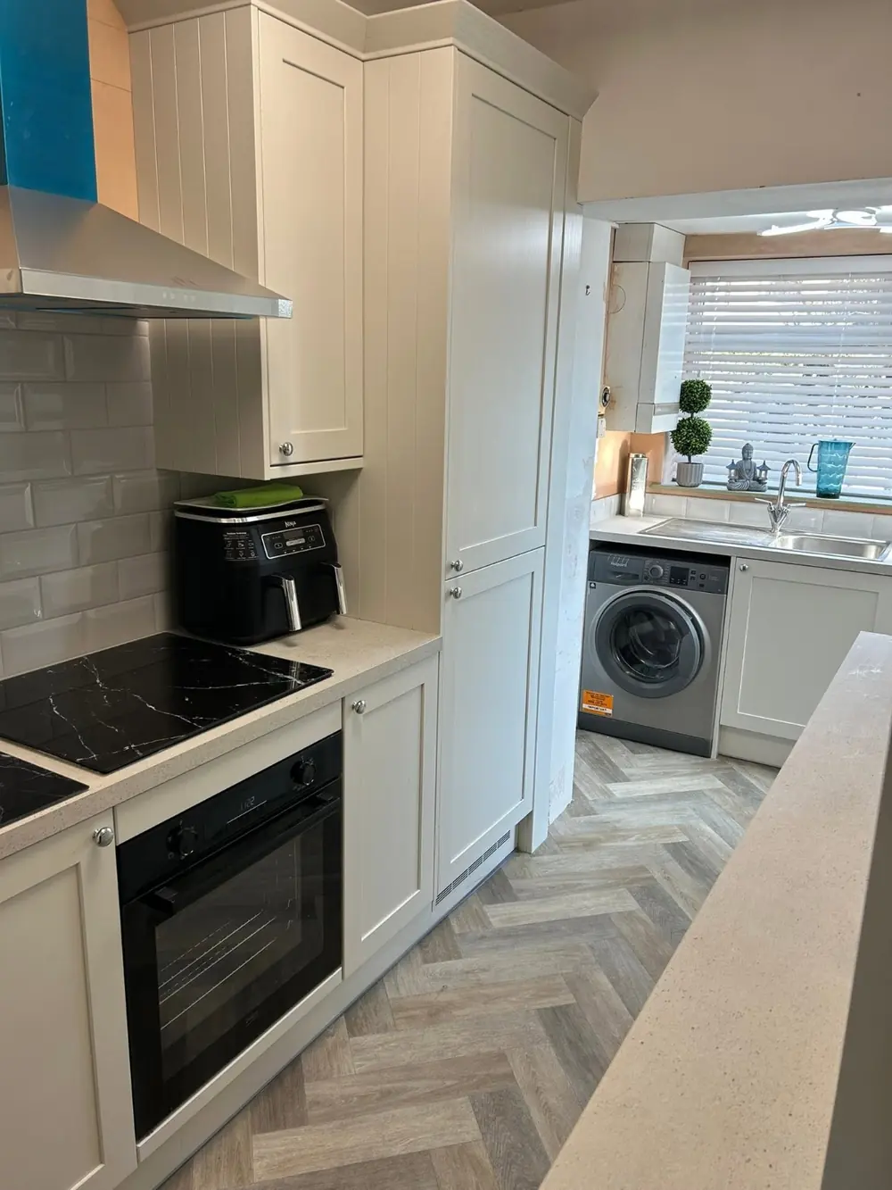 Cream shaker kitchen with metro tile splashback and herringbone flooring